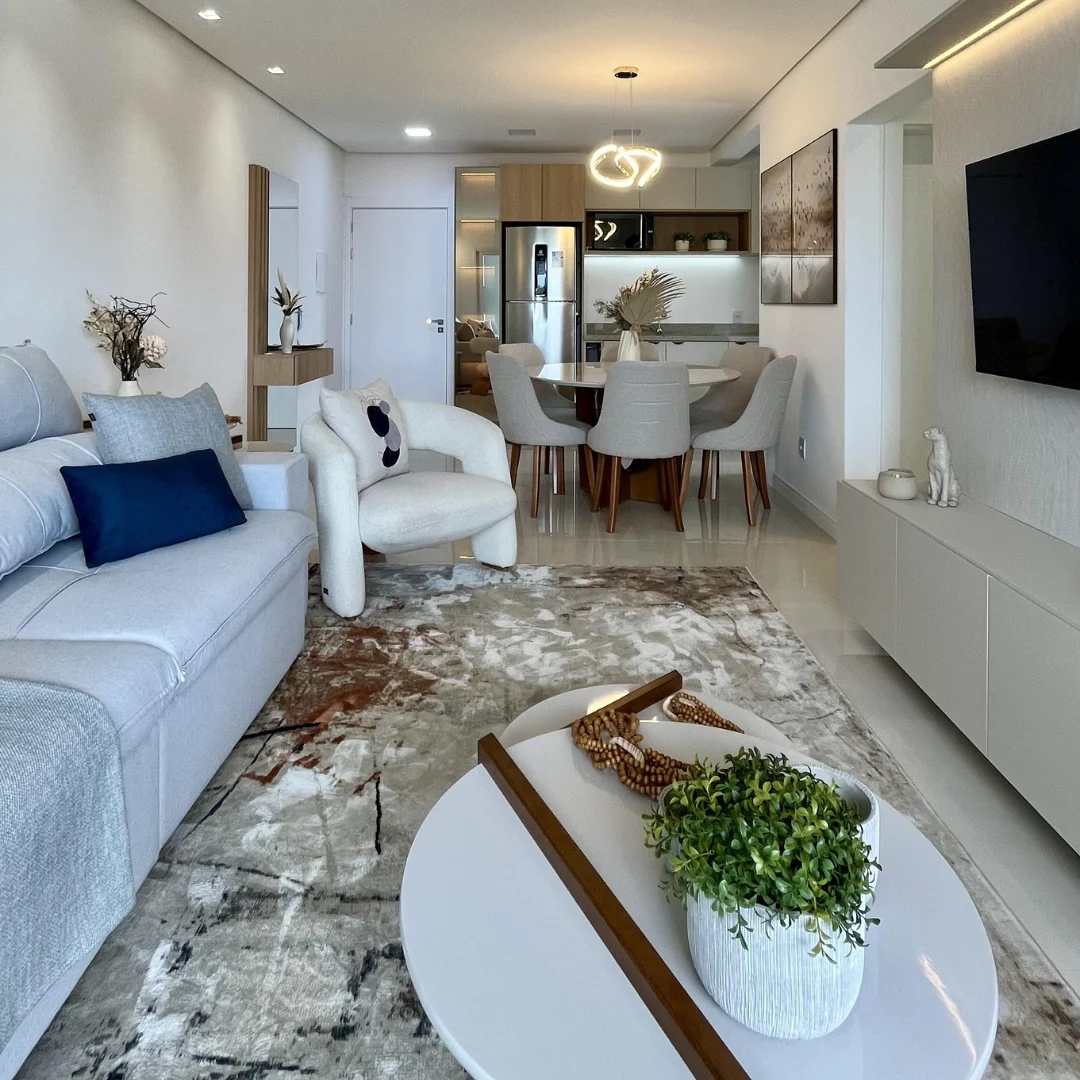 Sala integrada clara com painel de TV e mesa de jantar ao fundo